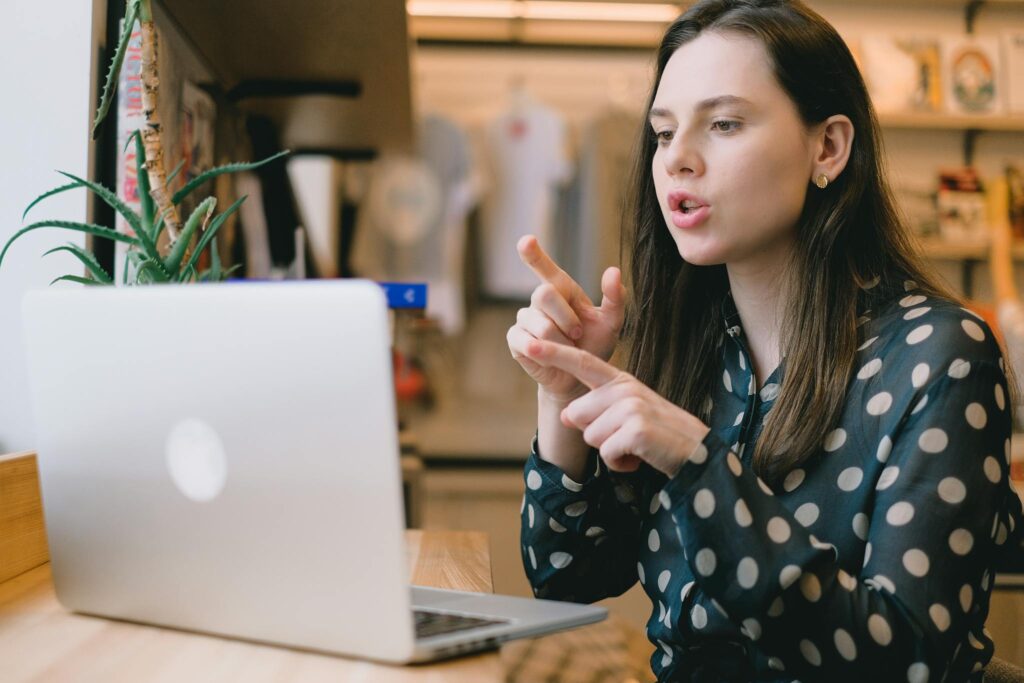 Focused young woman having video call on netbook in modern workspace